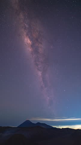 
Time lapse The Milky Way above Mount Bromo shimmers beautifully. and perpendicular to the peak of Mount Bromo that is constantly spewing out white smoke.Vertical video of the Milky Way at Mount Bromo
