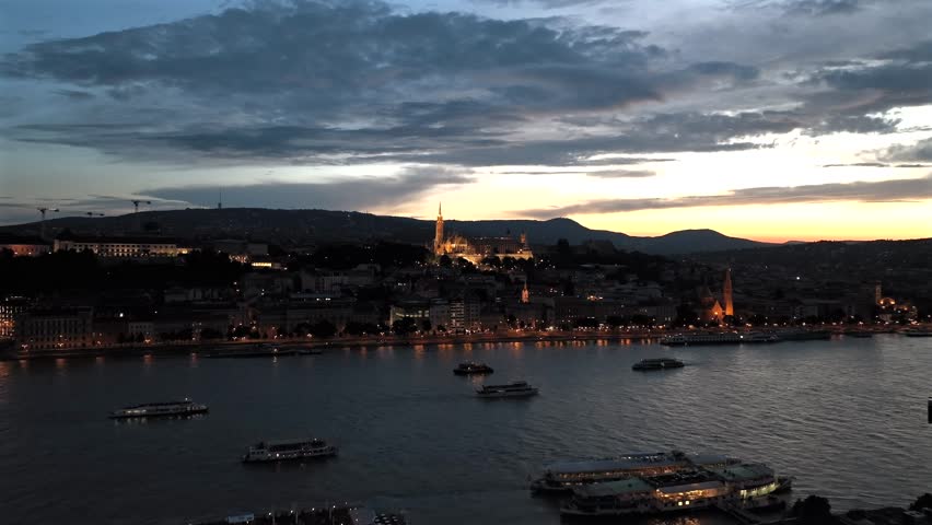 Aerial movie about the Budapest at dusk. Ricer cruises on de Danube river and Fishermans bastion on the background
