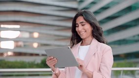 Smiling young middle eastern Israel businesswoman using tablet pc application for online remote work standing at office business building outdoors. Indian or arabic 30s woman holding digital computer - Powered by Shutterstock - Get 15% off with code: PIKWIZARD15