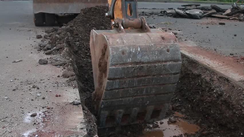  Excavator digs trench in the construction site, close up backhoe digger