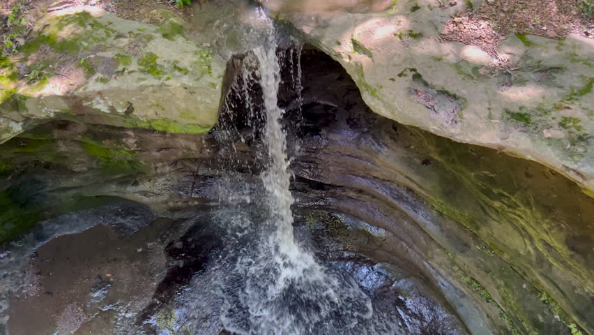 Beautiful waterfall against sandstone cliffs at Starved Rock State Park in Illinois. Stationary views as the water flows downward into a canyon.