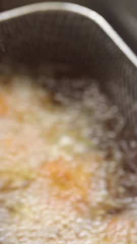 Deep-fried Crispy Chicken Drumsticks in Deep Fryer Basket and Lift Them Out of The Boiling Oil. Close-up Shot