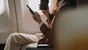 Young Asian woman uses mobile phone to check news information Sitting near the window in business class, airplane class during flight, travel and business concept - Powered by Shutterstock - Get 15% off with code: PIKWIZARD15