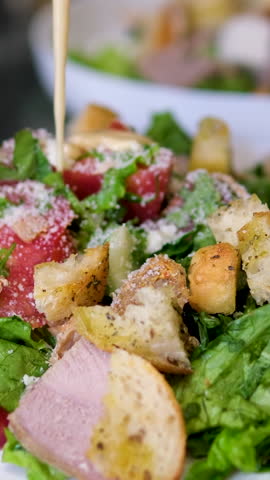 Close up shot of cooking Caesar salad inside deep cooking bowl. Chef cooking Caesar. Cooking process.