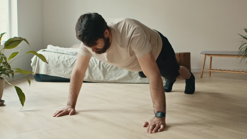 Home training. Strong bearded man doing push ups exercise at home in morning