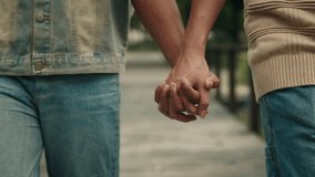 Young boyfriends join hands walking together along city street closeup. Homosexual couple of male partners enjoys romantic date. LGBT community pride month celebration activities - Powered by Shutterstock - Get 15% off with code: PIKWIZARD15