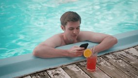 A relaxed young man with a cocktail is using a smartphone while enjoying the pool - Powered by Shutterstock - Get 15% off with code: PIKWIZARD15