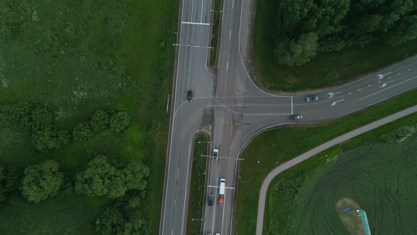 Aerial view of a rural intersection with moderate traffic, green landscape, and smooth countryside roadway