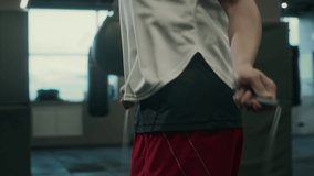 Medium close-up tilt shot of midsection and face of young Hispanic female boxer with short dark hair doing cardio warm-up before training with jumping rope alone at professional gym - Powered by Shutterstock - Get 15% off with code: PIKWIZARD15