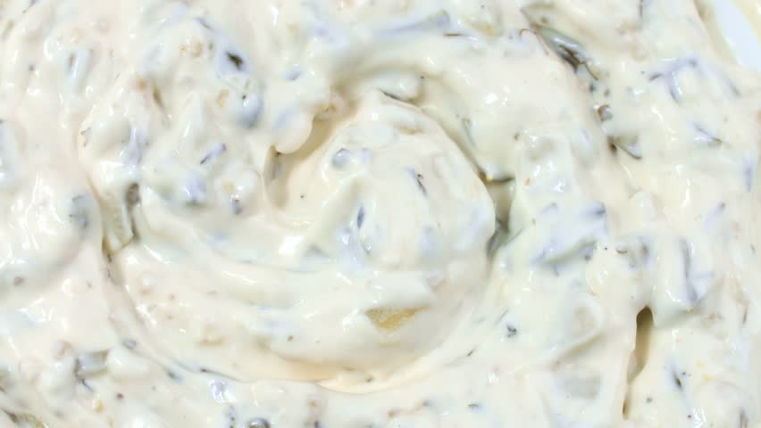 Tartar sauce with onions and pickled cucumbers circle rotation close up top view
