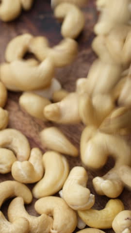 Cashew nuts falling down in plate, top view. Healthy Food concept. sstkVertical