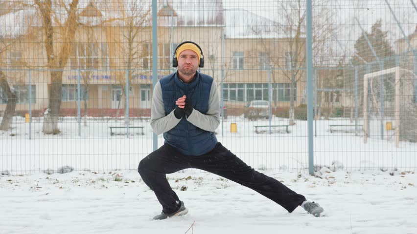 A young adult man trains his body and mind through outdoor gymnastics during wintertime, with headphones providing musical motivation.