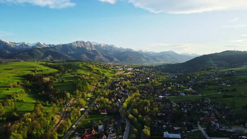 Aerial view of Tatra mountains and Zakopane town at sunset. Panoramic landscape with mountain ranges and green valleys near village. View on Giewont, Poland