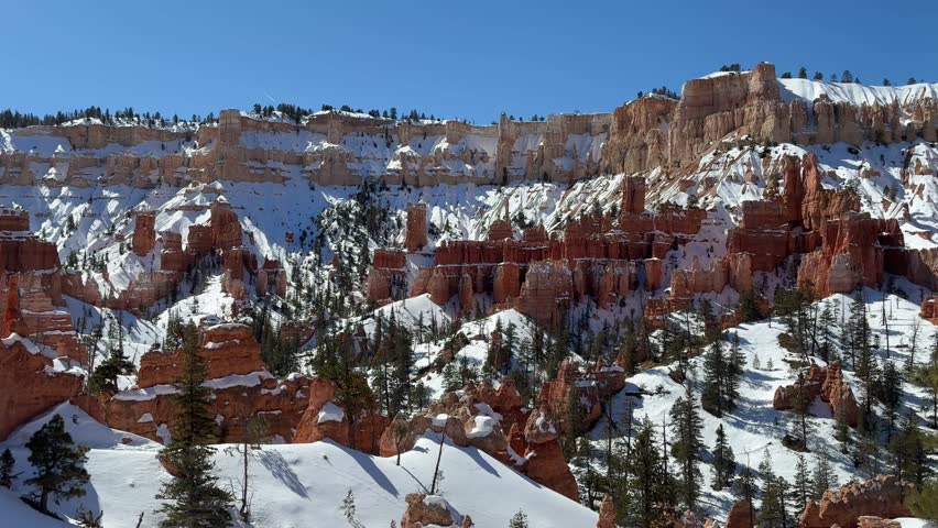 Beautiful snow covered red rock hoodoo formations at Bryce Canyon National Park, Utah, USA. Taken from within the canyon during winter looking up at the rim.