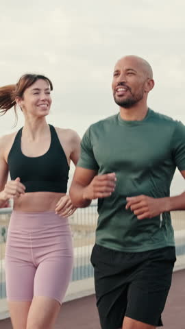 Vertical video, Close-up of couple, man and woman running or jogging at the seaside for a healthy lifestyle. Street work out concept, couple goals and motivation