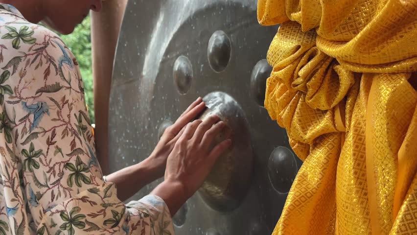 Woman doing with her hands healing sounds on ancient Thai temple gong