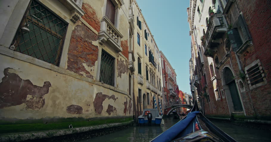 View from a gondola floating on the canals of Venice, Italy. A boat sails along romantic canals in a beautiful cityscape of a tourist city in Europe. High quality 4k footage