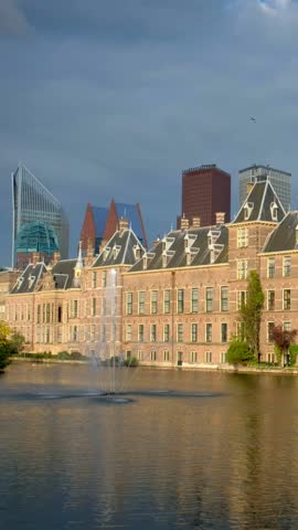 View of the Binnenhof House of Parliament and the Hofvijver lake with downtown skyscrapers in background. The Hague, Netherlands. Camera pan