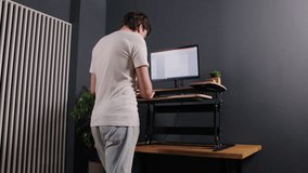 Keying computer, typing standing, keyboarding machine. Man in white shirt typing on computer at standing desk viewed from behind, with document on screen. - Powered by Shutterstock - Get 15% off with code: PIKWIZARD15