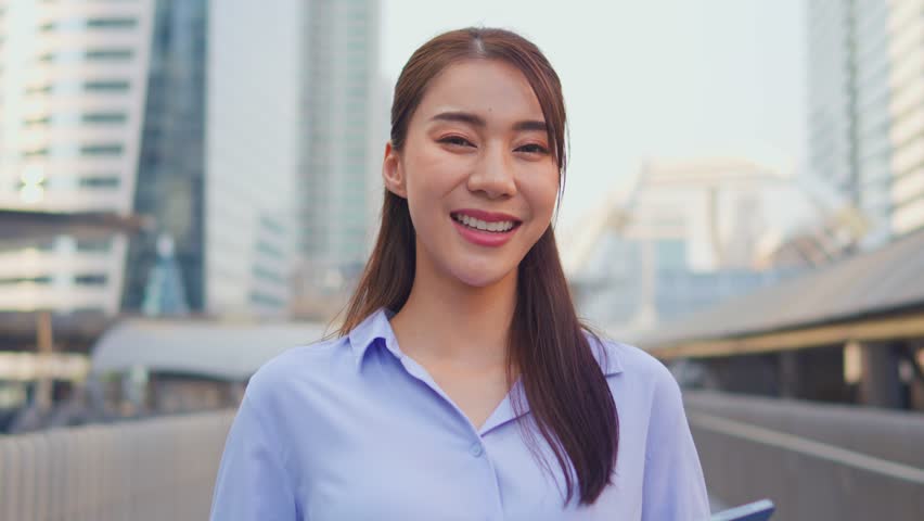 Portrait of Asian youg beautiful businesswoman standing outdoor in city. Attractive employee girl worker feel happy and confident then smile, looking at camera. Job application and recruitment concept
