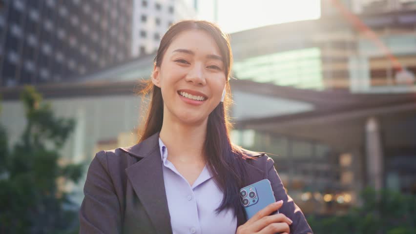 Portrait of Asian youg beautiful businesswoman standing outdoor in city. Attractive employee girl worker feel happy and confident then smile, looking at camera. Job application and recruitment concept