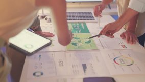 Business team members collaborate over printed ESG reports and digital devices, strategizing on sustainability initiatives and renewable energy investments in an office space. - Powered by Shutterstock - Get 15% off with code: PIKWIZARD15