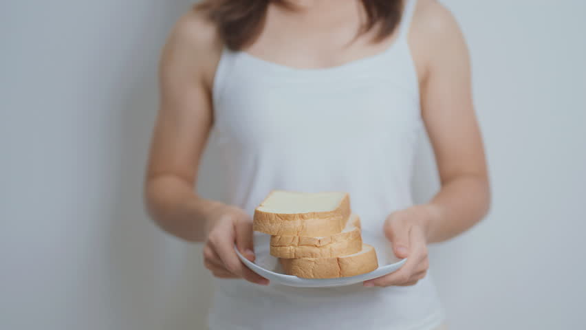 Bread eating and Daily Routine concept. Young woman Hand holding sliced whole grain bread in the morning at home
