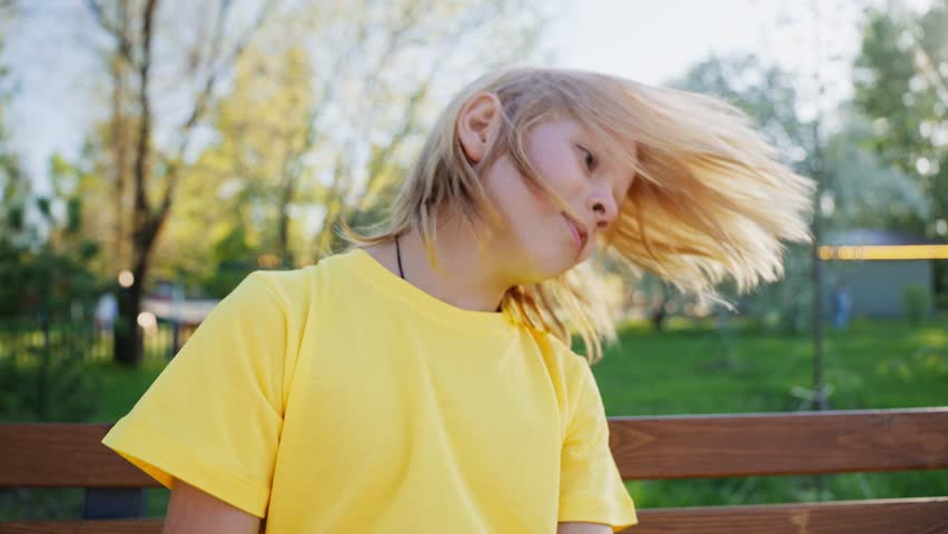 Slowmo waist up portrait of Caucasian teen boy posing for camera back outdoors in summer. 