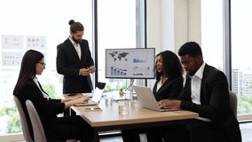 Businessman reports to colleagues standing near graphs and charts on monitor, screen, display. Conference room with professionals discussing financial data. Team meeting emphasizing business strategy. - Powered by Shutterstock - Get 15% off with code: PIKWIZARD15