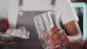 Barman pours ice pieces with scoop into glass closeup. Black bartender prepares ice cubes for refreshing cocktail. Fresh beverages for visitors in bar - Powered by Shutterstock - Get 15% off with code: PIKWIZARD15