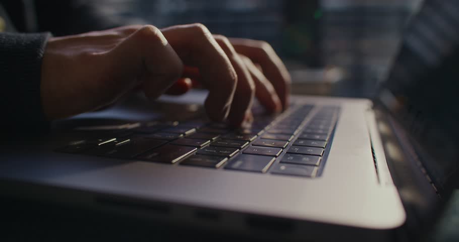 Close camera view of person working on laptop. Man typing something on keyboard. Mailing with someone. Actively pressing keys down of technology device. Network. Web and digital concept.