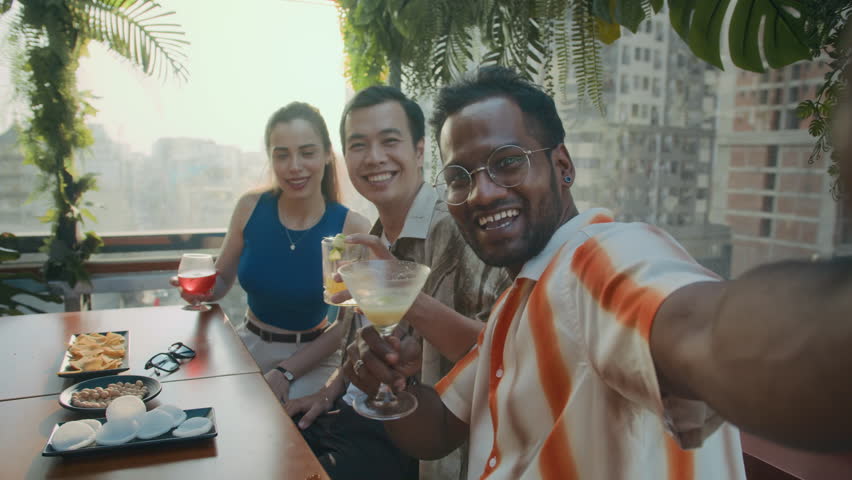 POV of three diverse friends taking selfie while having drinks, meeting at trendy cafe