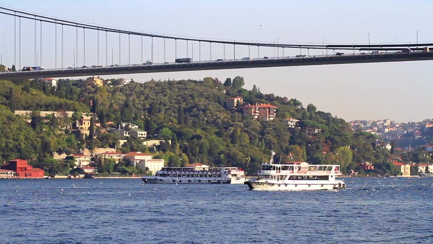City cruise ships sailing under the Bosporus Bridge 

