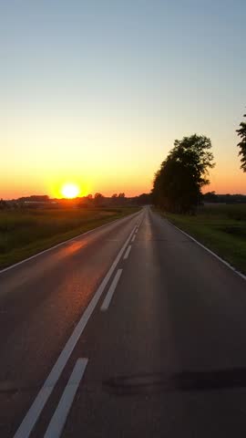 On a rural road to sunset, vertical pov
