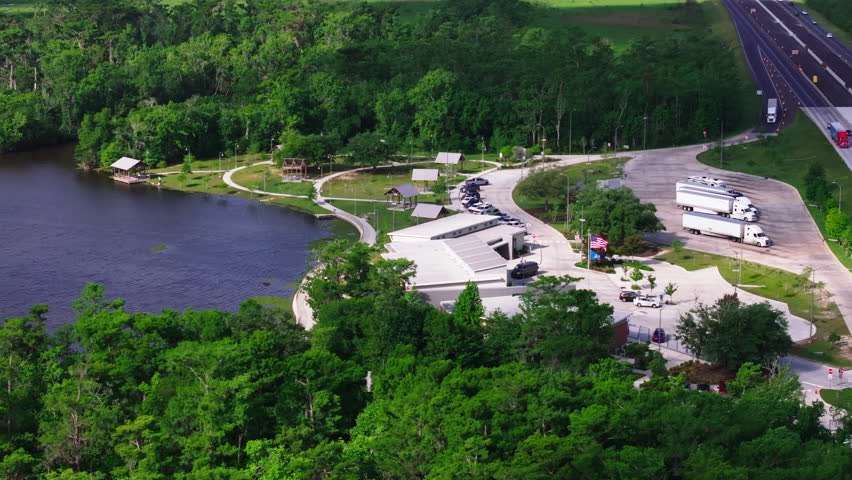 Tranquil american rest area with greenery and a serene river. People unwind in the peaceful natural setting, surrounded by parked vehicles