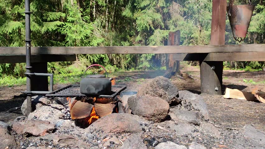 Small kettle is heated on a bonfire. Hiking, travel in the mountains. Outdoor recreation concept. Finland.