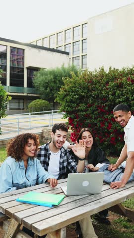 Collaborative multi-ethnic students working together at picnic table.  Diverse students collaborate on a project outdoors at a picnic table with a laptop