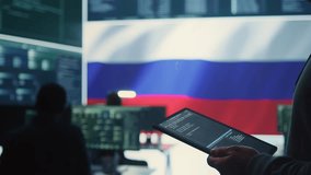 Person uses tablet in governmental cyber security room working under the Russian flag. Making cyber threats, hacking systems to gain unauthorized access, and spreading fake news. Close up. Camera B. - Powered by Shutterstock - Get 15% off with code: PIKWIZARD15