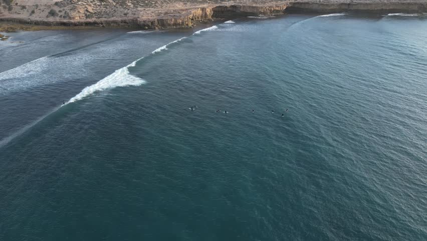 Birds eye view over cactus beach and the surfers on the water. Tilting shot.