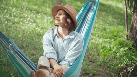 A young Caucasian woman in a hat chilling in a hammock in the spring garden - Powered by Shutterstock - Get 15% off with code: PIKWIZARD15