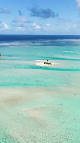 Small Motu islet in tropical sandbar and turquoise Pacific water vertical video.