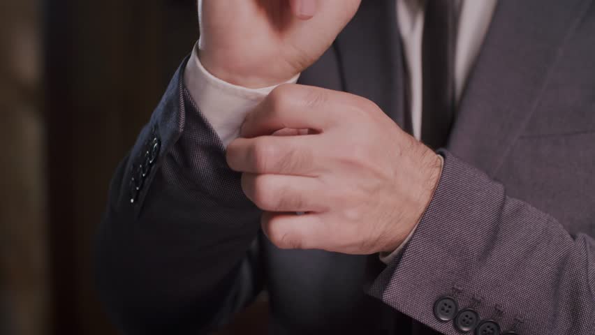 A businessman adjusting his suit cuffs during a corporate meeting for a polished look