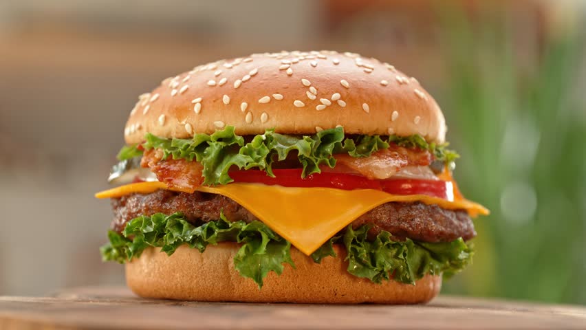 Tasty home made burger with camera movement and rotating . Delicious burger with fresh cabbage, cheese, onions, bacon, tomatoes and grilled beef steak.
