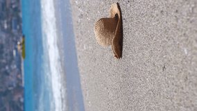 Straw hat on a sand beach of sea. Vertical video. - Powered by Shutterstock - Get 15% off with code: PIKWIZARD15