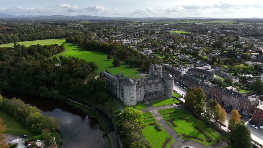Kilkenny Castle, County Kilkenny, Ireland, September 2023. Drone orbits from the River Nore across the elegant formal gardens with the Blackstairs Mountains of County Carlow in the distance.