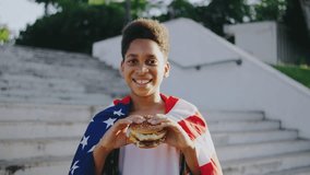 Under the sunny sky, a cheerful, patriotic boy joyfully eats a burger wrapped in the American flag outdoors, celebrating freedom and showing love for his country with pride and joy - Powered by Shutterstock - Get 15% off with code: PIKWIZARD15