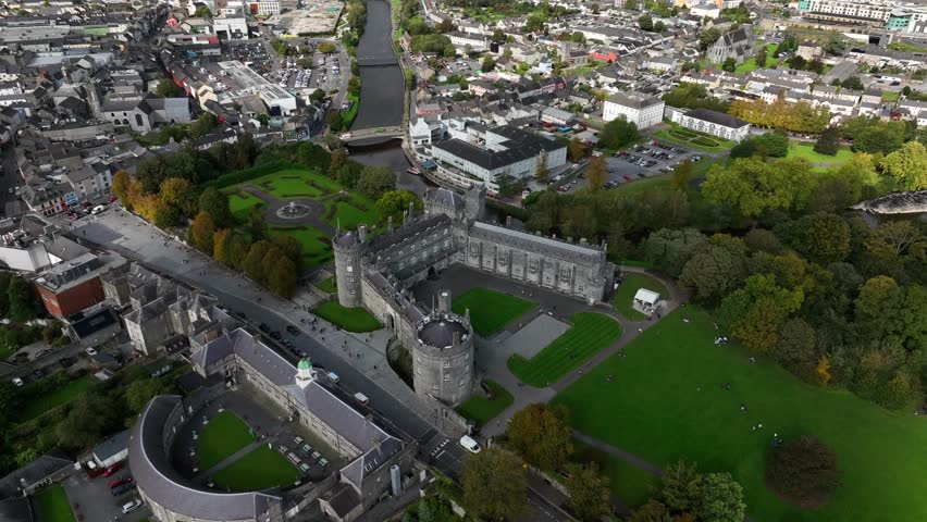 Kilkenny Castle, County Kilkenny, Ireland, September 2023. Drone orbits away from the historic building as shadows glide across the city with Saint Canice and Mary