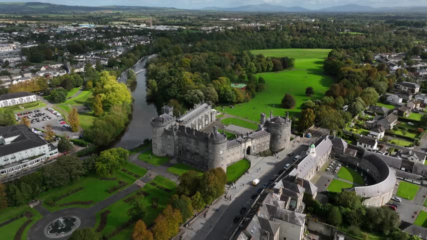 Kilkenny Castle, County Kilkenny, Ireland, September 2023. Drone locked in a station position as clouds and shadows roll across River Nore and green landscape.