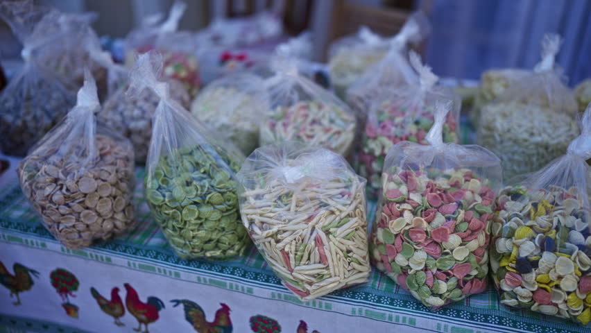 Bags of colorful italian pasta displayed on a vibrant market table outdoors in bari, italy, showcasing traditional puglian food.