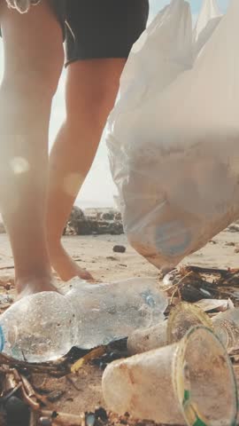 Cropped woman environmental activist wearing gloves alone cleans sea beach and bags bottles to raise public awareness of sustainable development goals located on south island. Pollution, emissions